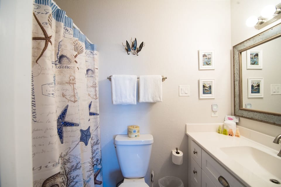 Step into your nautical-themed bathroom with charming coastal decor and fresh towels waiting for your arrival.