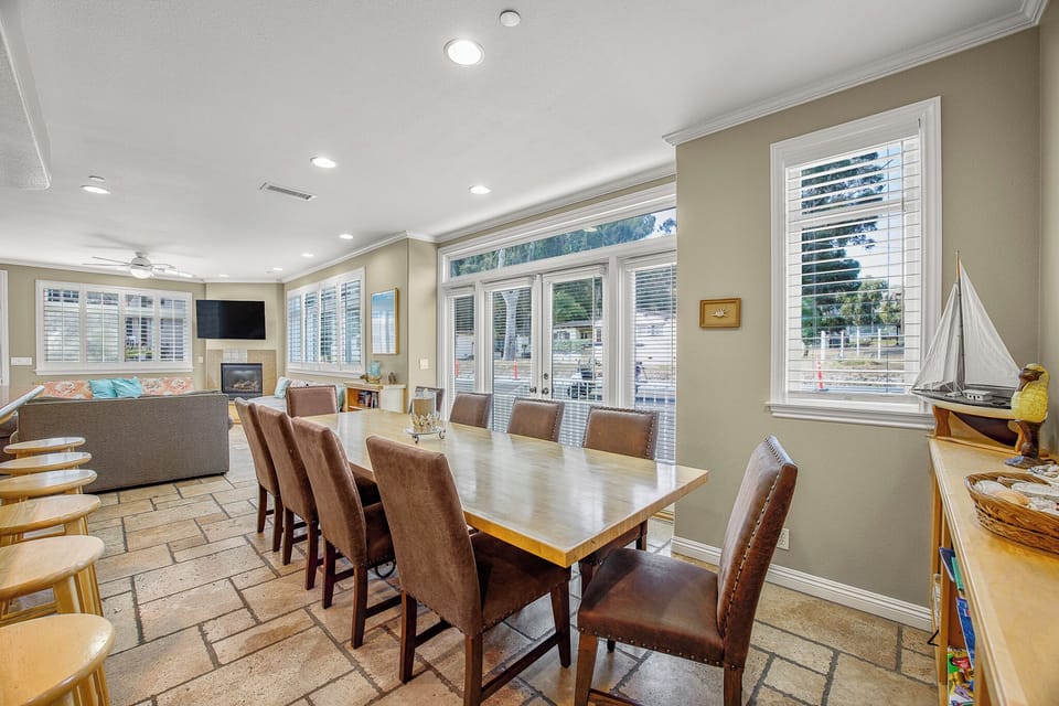 Gather your group around this spacious dining table where natural light streams through floor-to-ceiling windows, creating the perfect setting for memorable meals together.