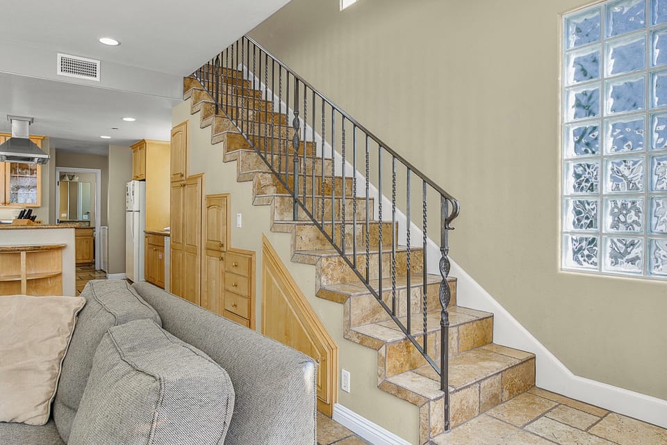 Your spacious living area flows seamlessly with elegant stone stairs leading to upper levels, while warm wood cabinetry completes this inviting home.