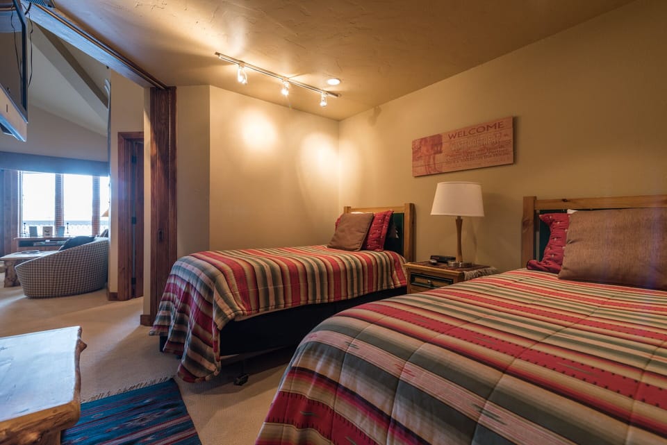 Unwind in your cozy twin bedroom featuring warm wood accents, vibrant striped bedding, and a welcoming atmosphere perfect for restful nights.