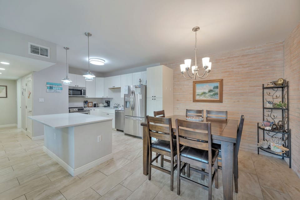Your open-concept kitchen and dining space features white cabinetry, granite counters, and modern appliances perfect for preparing memorable vacation meals together.