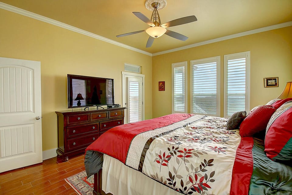Unwind in your peaceful retreat with colorful linens, ceiling fan, and stunning views through multiple windows.