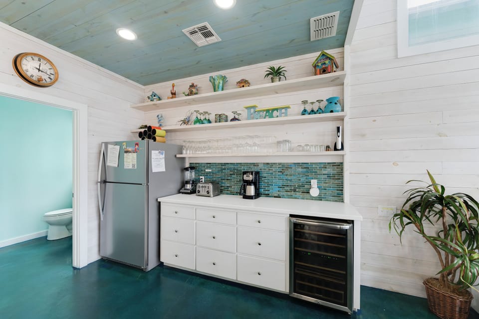Your charming coastal kitchen features modern appliances, ocean-inspired décor, and open shelving perfect for preparing memorable vacation meals together.