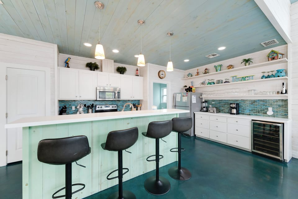 Your coastal-inspired kitchen awaits with turquoise accents, spacious island seating, and everything needed for memorable meal prep.