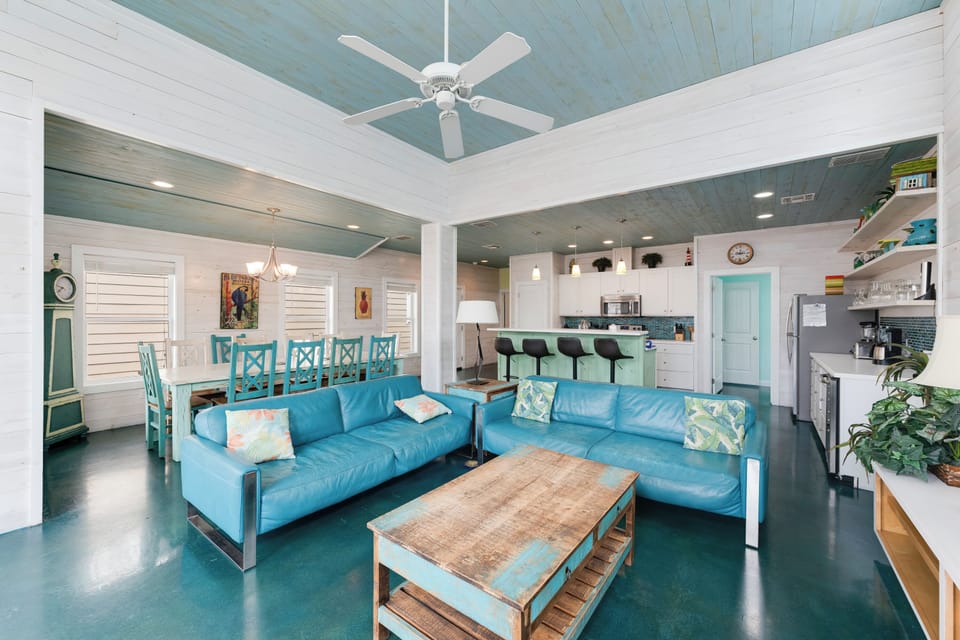 Relax in your spacious open-plan living area with coastal blue sofas and stunning turquoise ceiling beams overhead.