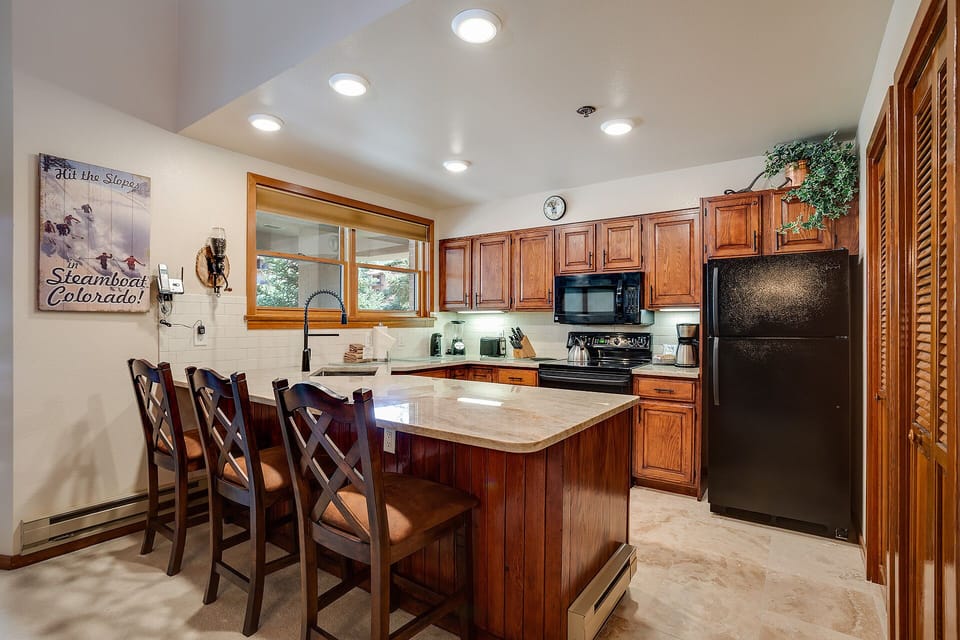 Your fully equipped kitchen features rich wood cabinets, granite countertops, and modern appliances, perfect for preparing family meals during your mountain getaway.