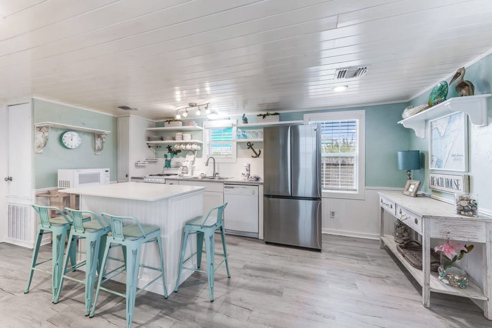 Your spacious kitchen features coastal charm with turquoise accents, modern appliances, and a welcoming breakfast bar perfect for morning coffee.