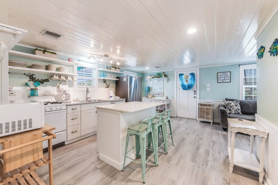 Step into your coastal-themed kitchen with mint bar stools and white shiplap ceiling, where cooking becomes a joy.