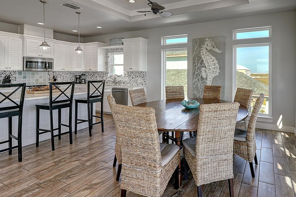 Gather around this spacious dining table where coastal charm meets modern comfort, perfect for memorable meals with ocean views streaming through large windows.