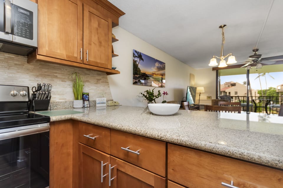 Your vacation begins in this beautifully appointed kitchen with gleaming granite counters, warm wood cabinetry, and modern appliances. Natural light floods through the open layout, connecting you to the inviting living space just beyond.