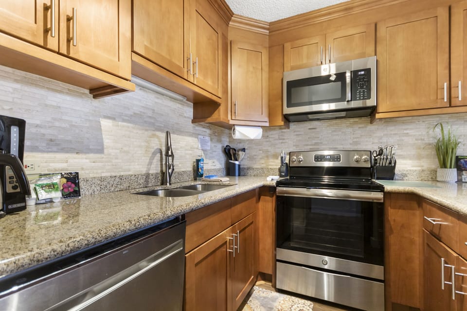 Your fully equipped kitchen features stainless steel appliances, granite countertops, and warm wood cabinetry—everything you need to cook comfortably during your stay.