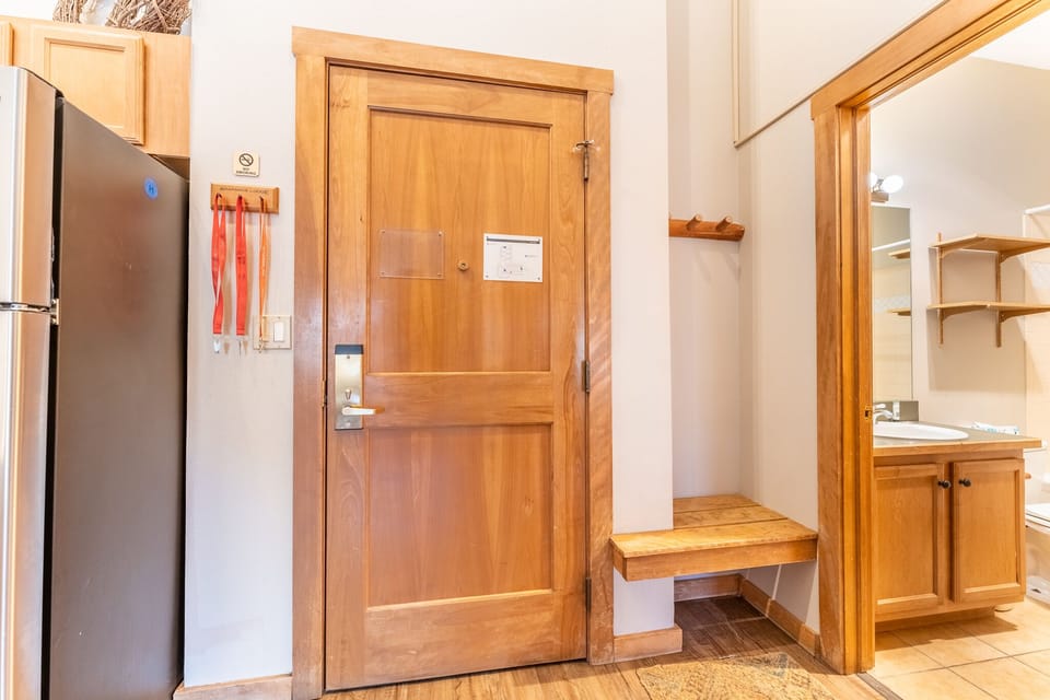 Step into your welcoming entryway with warm wooden details, handy bench, and glimpse of your private bathroom beyond.