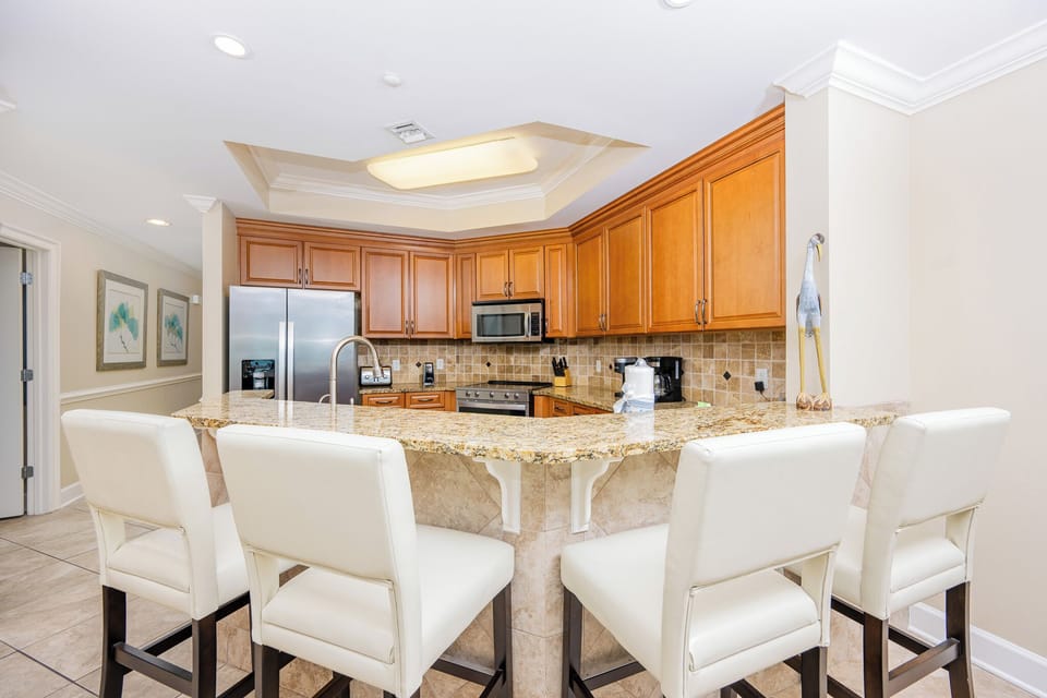 The kitchen features wood cabinetry, granite countertops, and stainless appliances, perfect for preparing meals
