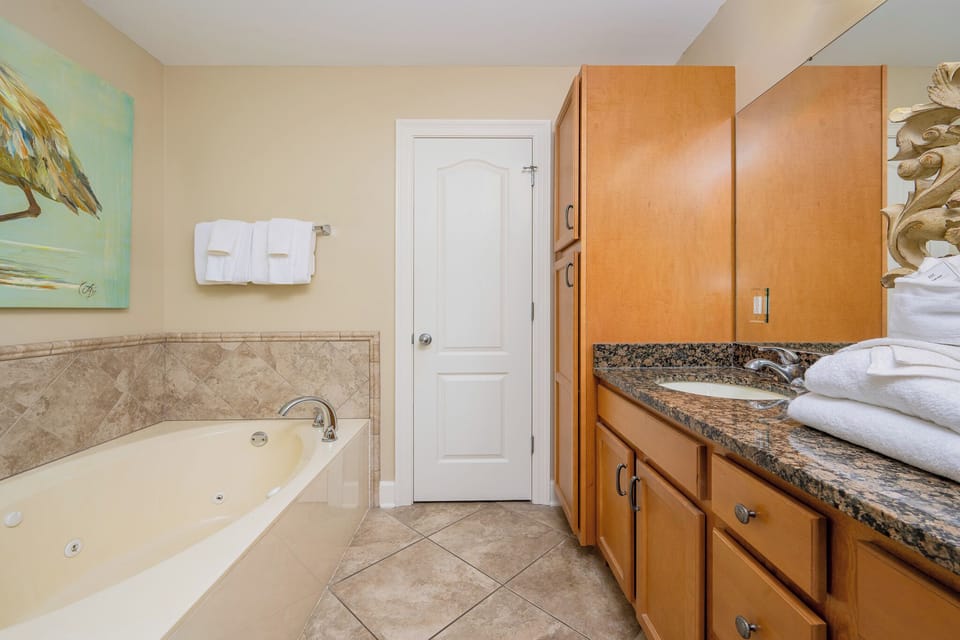 The master bath features a relaxing jetted tub, elegant granite countertops, and warm wood cabinetry for a serene retreat