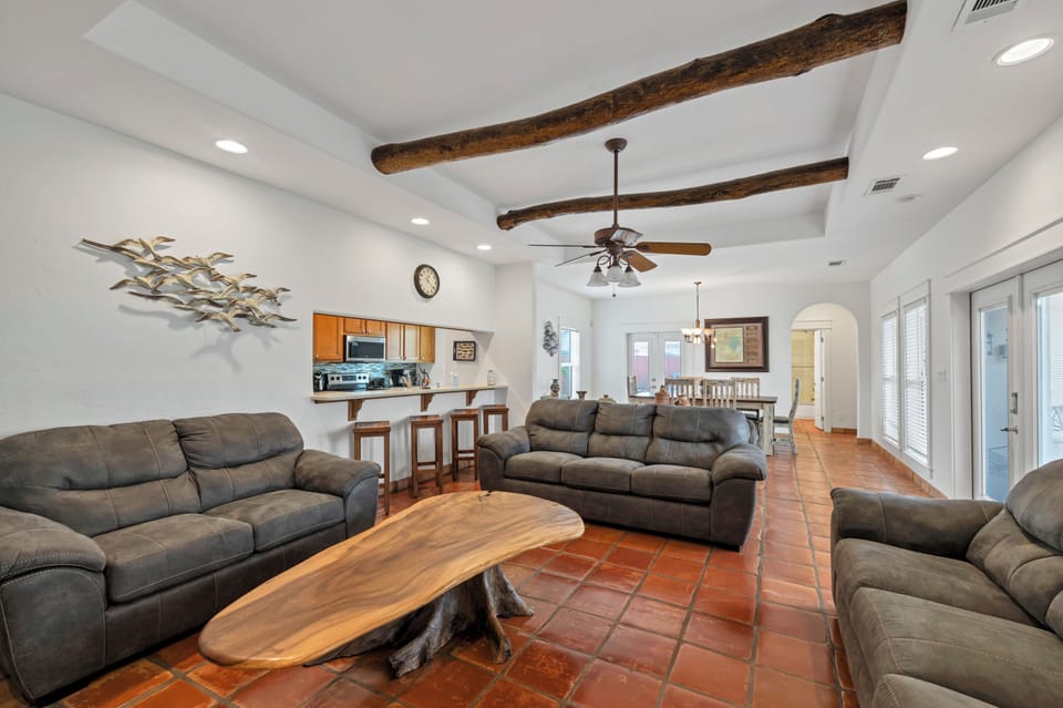 Relax in your spacious living area with exposed beams, comfortable seating, and an open kitchen perfect for gatherings.
