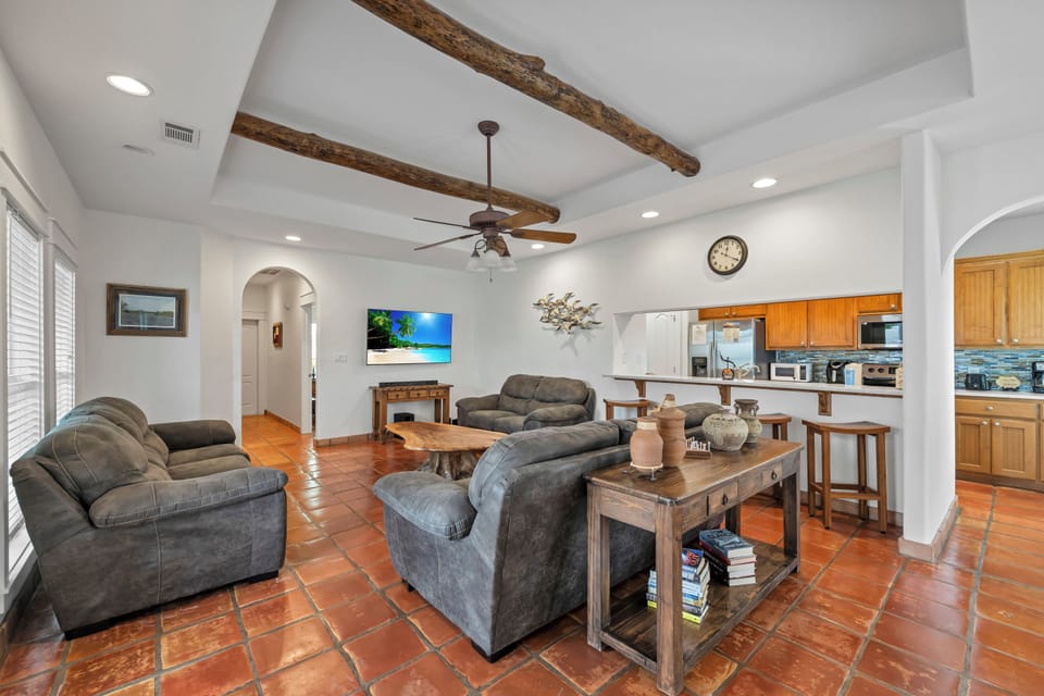 Relax in your spacious living room with rustic wood beams, comfortable seating, and an open kitchen perfect for gathering.