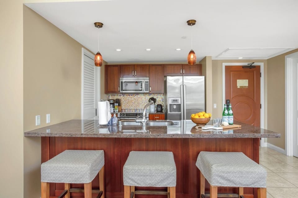 Modern kitchen with granite island, stainless appliances, and stylish lighting.