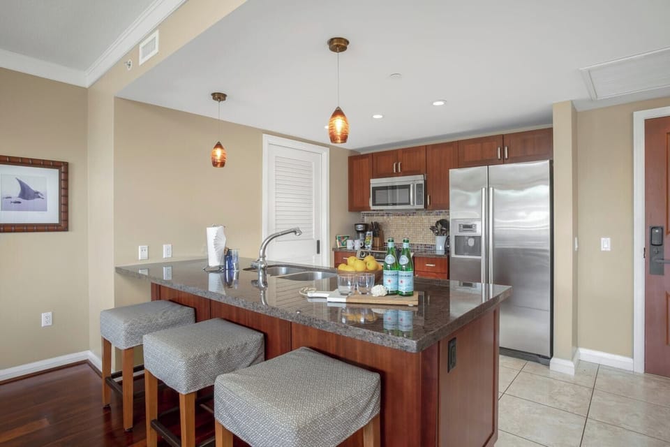     Sleek open-concept kitchen with granite counters and mosaic backsplash.