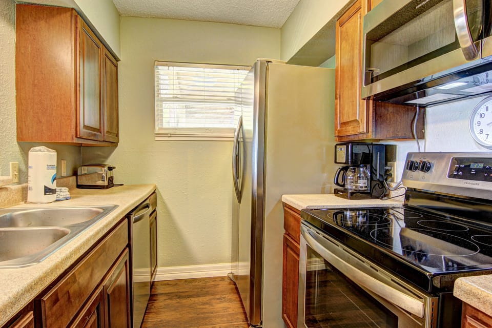 Your fully equipped kitchen awaits with stainless steel appliances and warm wood cabinetry, perfect for preparing meals.