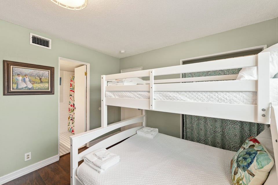 One of the twin-over-full bunk beds showcases comfortable sleeping accommodations with fresh linens, soft lighting, and thoughtful touches for a restful night's sleep.