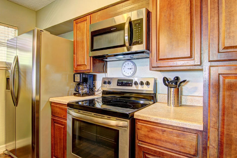 Cook your favorite meals in this well-equipped kitchen featuring stainless steel appliances, warm wood cabinetry, and granite countertops.