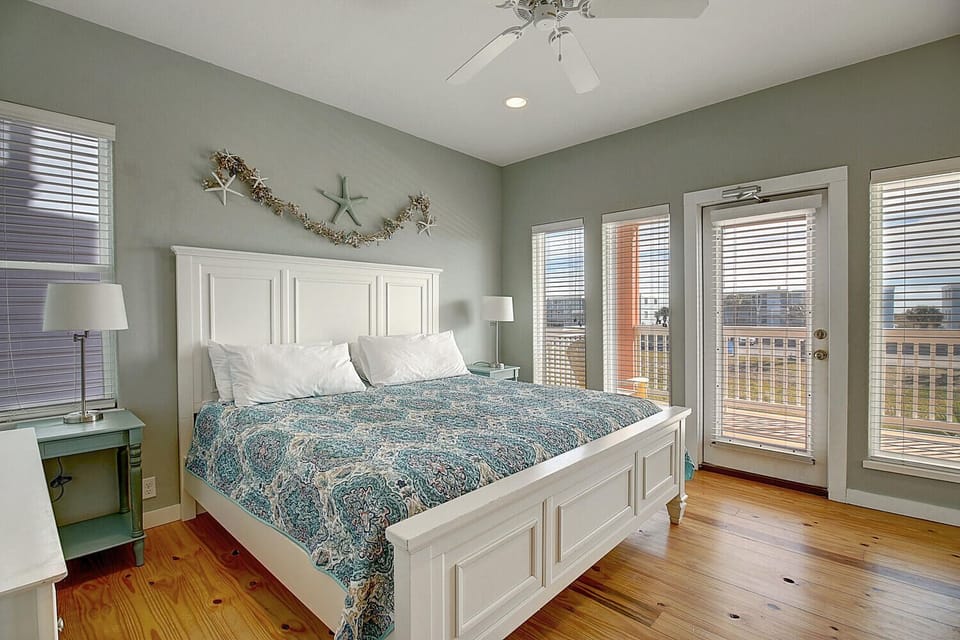 Drift off peacefully in this coastal-inspired bedroom featuring ocean-themed decor, a ceiling fan for comfort, and sliding doors to your private balcony.