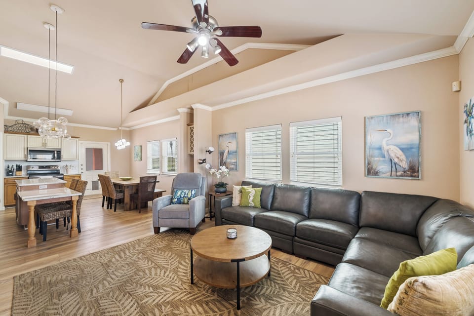 Gather in the inviting living area with plush seating, fresh coastal accents, and an open layout designed for relaxing after a day at the beach.