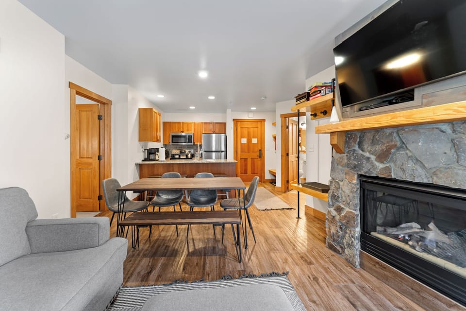 Gather around your dining table near the cozy stone fireplace in this open living space with a fully equipped kitchen.