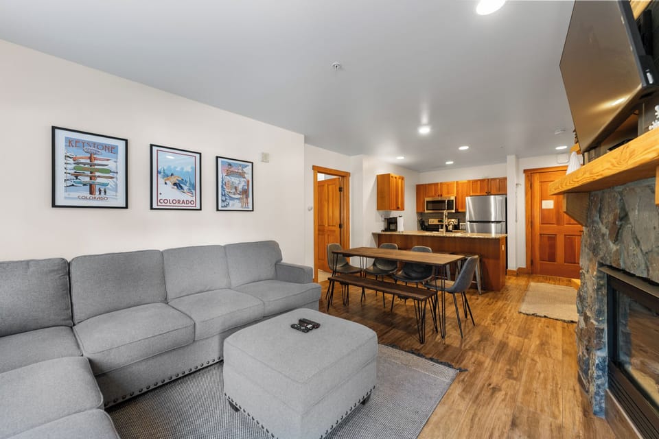 Cozy open living space with stone fireplace, modern kitchen, and Colorado artwork creates your perfect mountain retreat atmosphere.