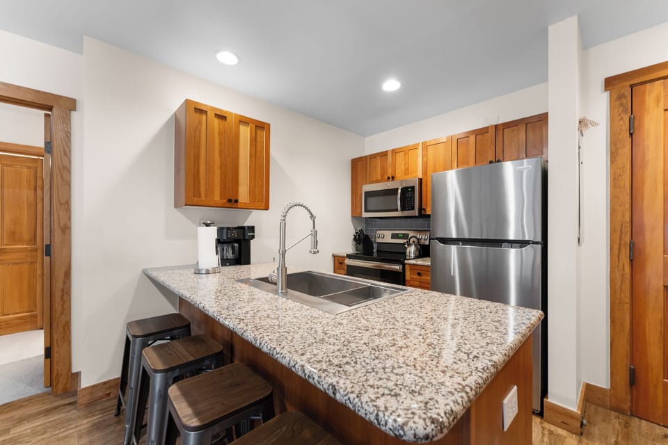 Your fully equipped kitchen features granite countertops, stainless steel appliances, and a breakfast bar perfect for morning coffee or casual meals together.