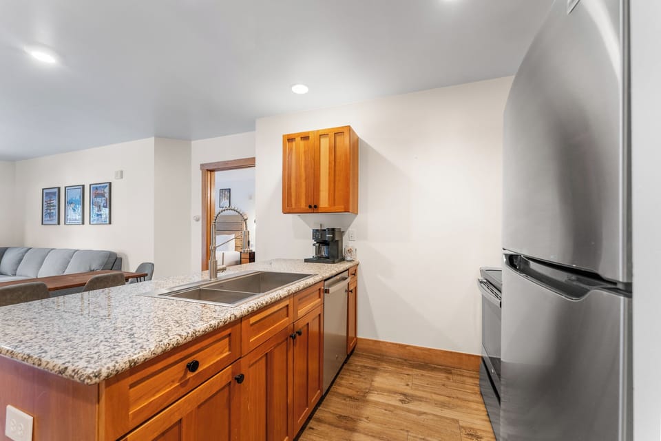 Your fully equipped kitchen features granite countertops, warm wood cabinets, and modern stainless steel appliances for convenient meal preparation during your stay.
