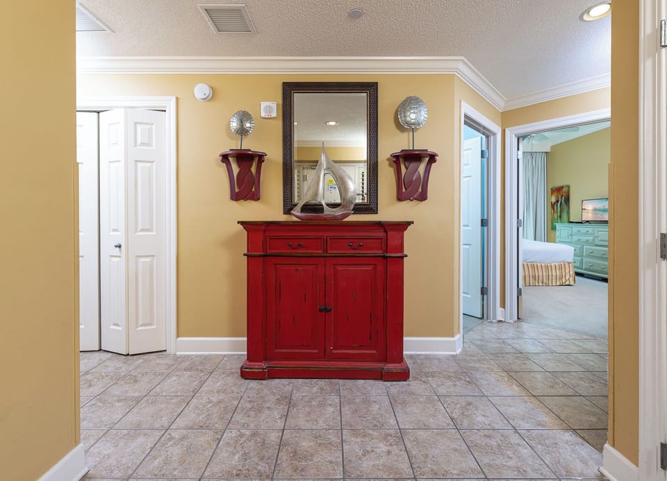 The hallway's textured tile leads you past cheerful decor toward restful guest suites and coastal views beyond