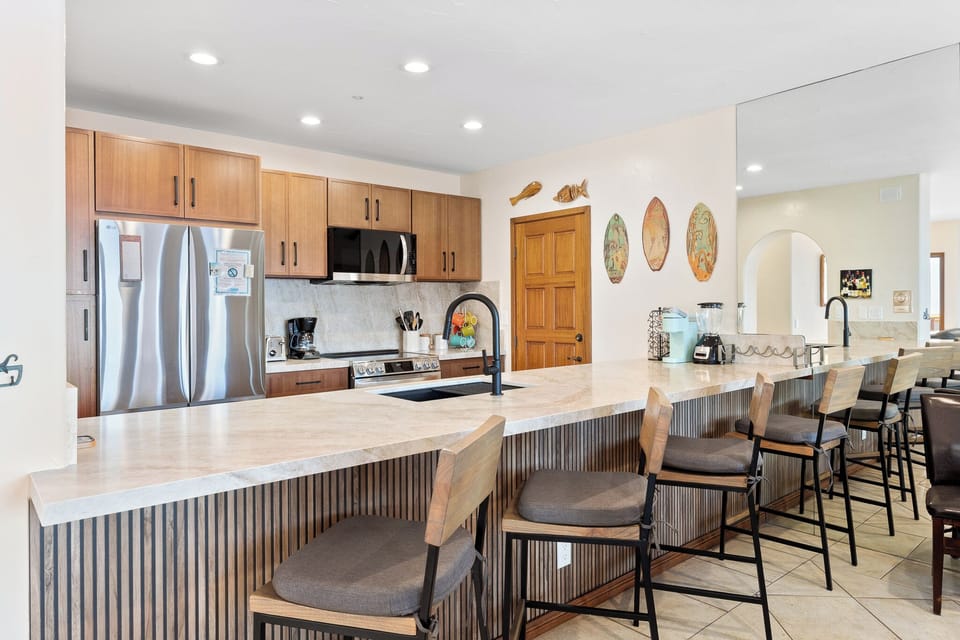 Your chef's kitchen awaits! Gather around the expansive island with seating for everyone, gleaming countertops, and modern appliances ready for cooking delicious meals together.