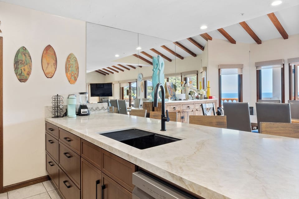 This open kitchen invites you to prepare meals on sleek marble countertops while soaking in stunning ocean views through expansive windows—perfect for cooking with a coastal backdrop.
