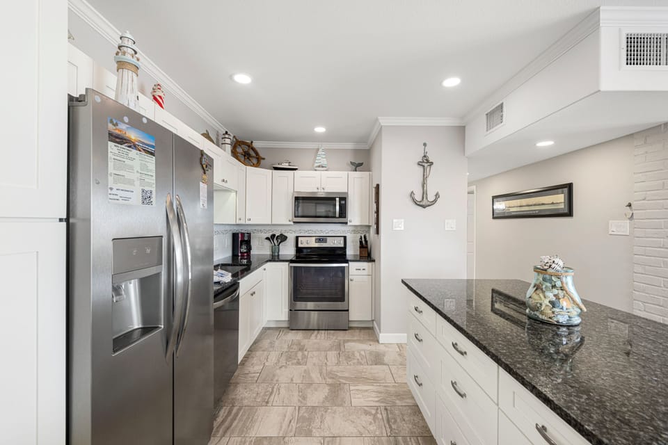 Your fully equipped kitchen features granite countertops, stainless steel appliances, and nautical touches that inspire culinary adventures during your coastal getaway.