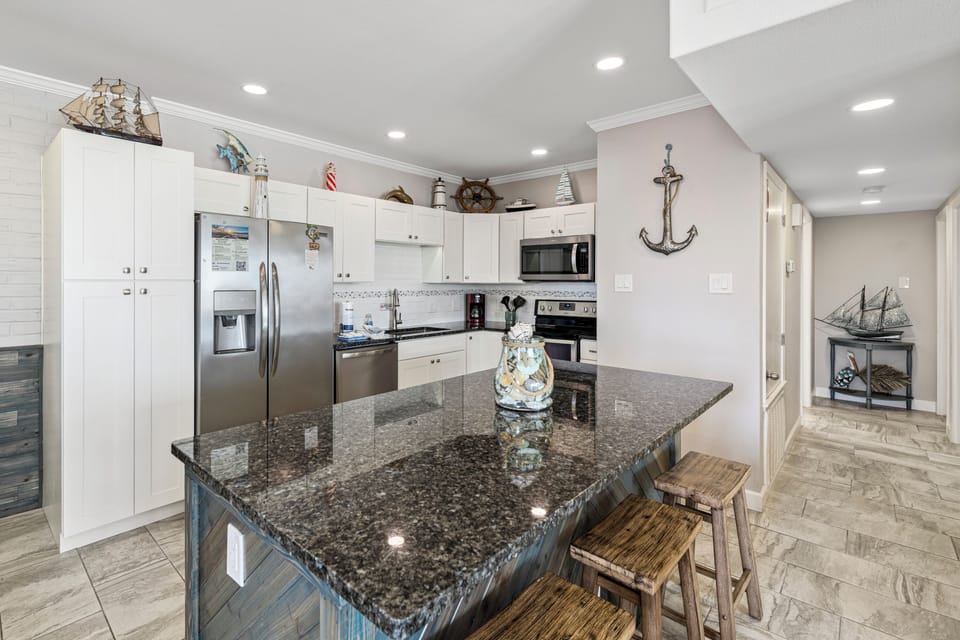 Your fully equipped kitchen features granite countertops, stainless steel appliances, and nautical touches that create the perfect space for cooking coastal meals.