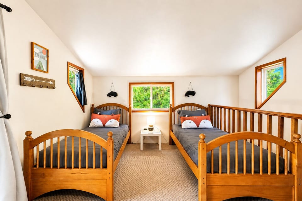 Your cozy retreat awaits with twin beds dressed in charming fox pillows, framed by warm wood tones and mountain views that bring nature right to your window.