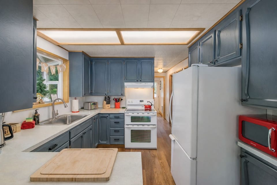 Your fully equipped kitchen features blue cabinetry, white countertops, and all modern appliances for comfortable cooking during your stay.