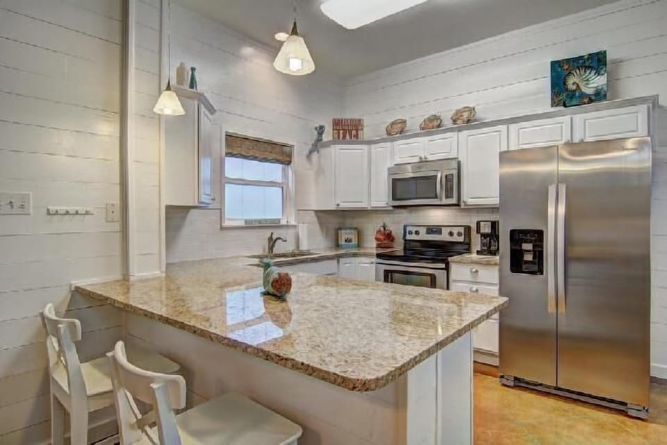 Your fully equipped kitchen features granite counters, stainless appliances, and coastal charm for creating memorable meals together.