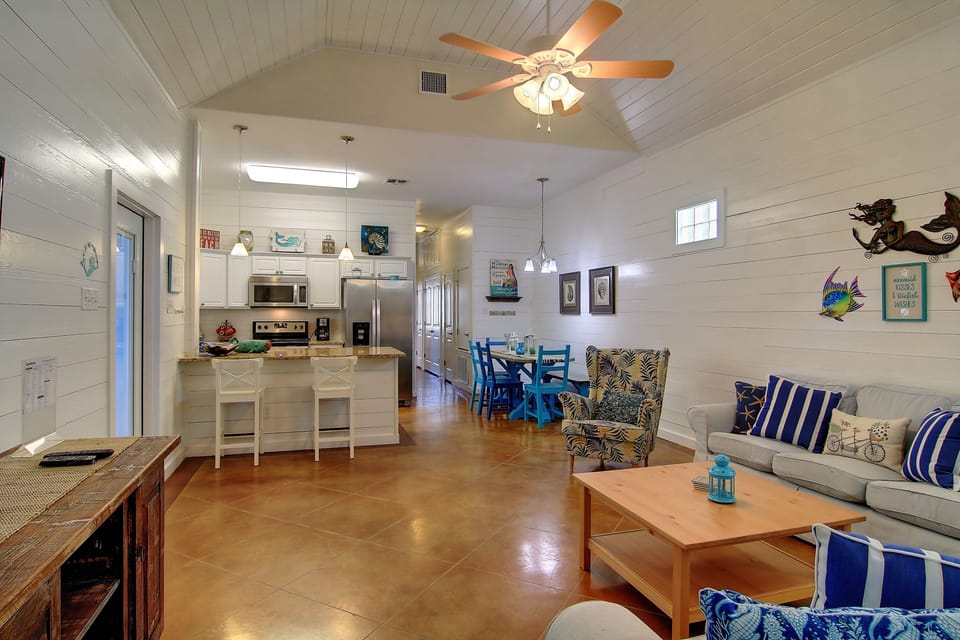 Relax in your bright open-plan retreat with coastal charm, where vaulted ceilings and cheerful blue accents create the perfect beach getaway atmosphere.
