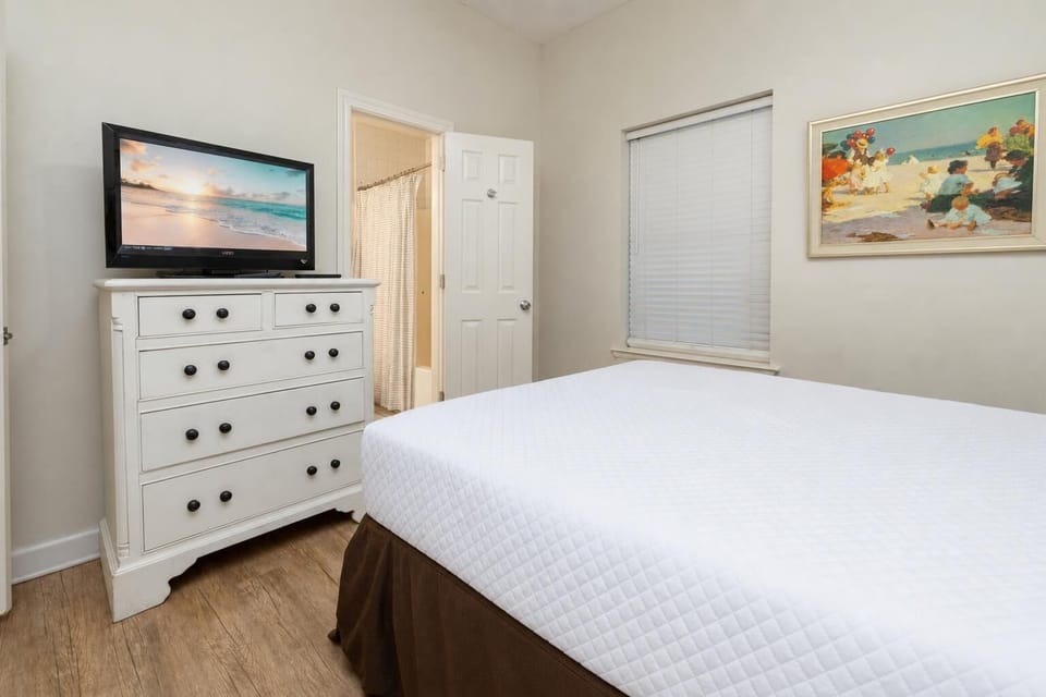 Inviting guest bedroom featuring a comfortable queen bed, a TV for entertainment, and natural light from the window