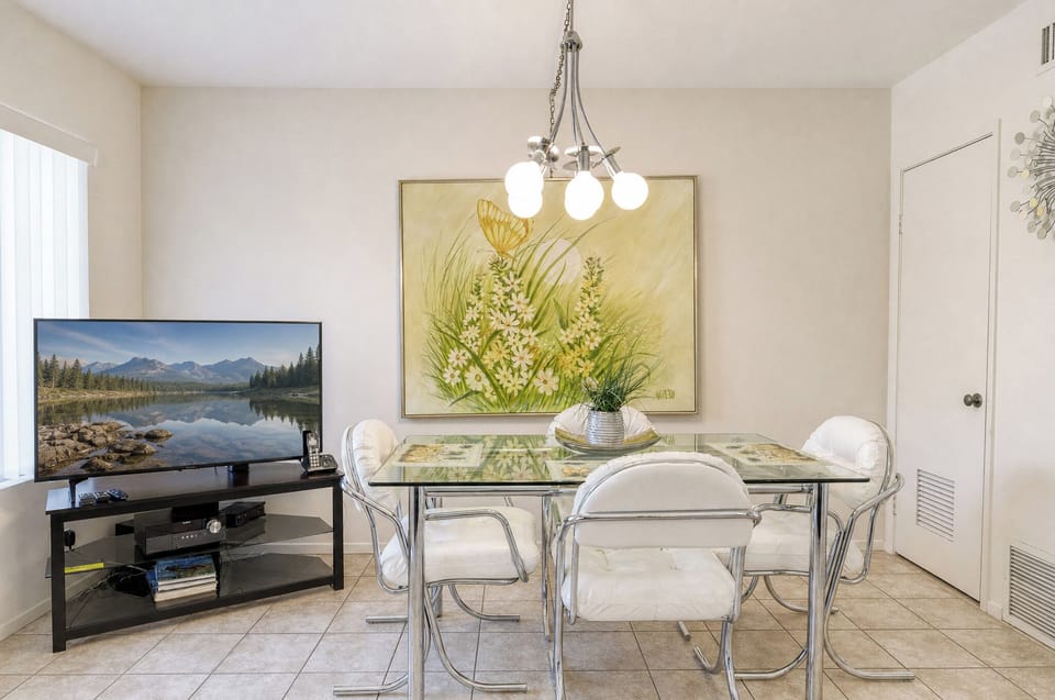 Your bright dining area features a glass-top table with contemporary seating, perfect for meals together under elegant lighting, with entertainment ready nearby.