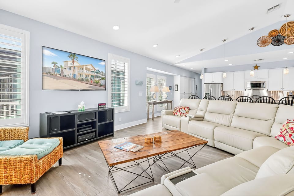 Unwind in your spacious living room featuring plush sectional seating, a large smart TV, and open-concept flow to the modern kitchen.