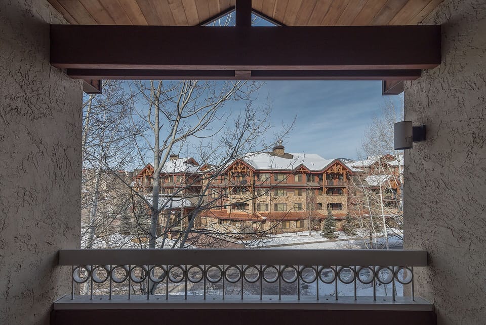 Cozy mountain lodge balcony frames snow-dusted chalets and winter wonderland views beyond your private retreat.