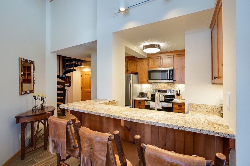 Your fully equipped kitchen awaits with granite counters, stainless steel appliances, and rustic bar seating for memorable mountain meals together.