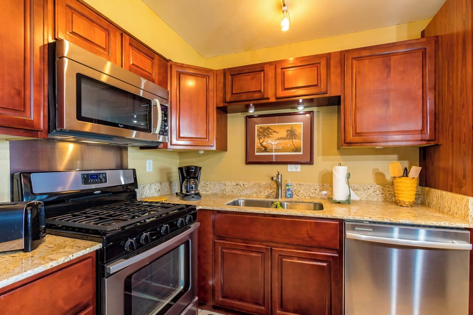 Your fully equipped kitchen features rich wood cabinetry, granite countertops, and stainless steel appliances—including a gas range, microwave, and dishwasher—ready for your home-cooked meals.
