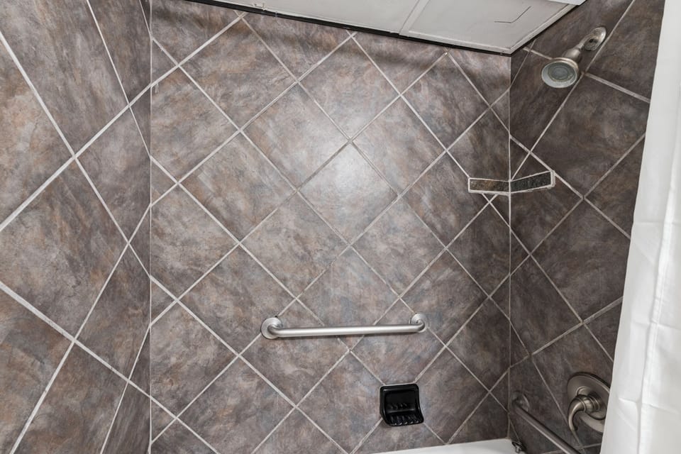 Step into your accessible walk-in shower with diagonal tile and convenient grab bars for safety and ease.