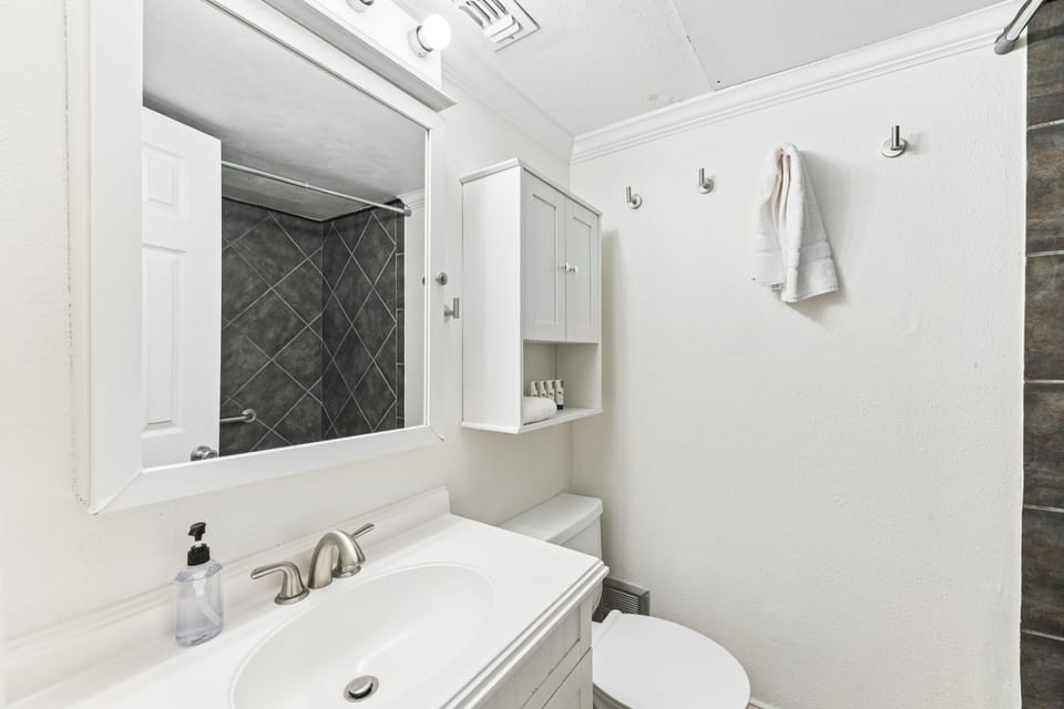 Step into a crisp, modern bathroom designed for your comfort, featuring a sleek vanity, fresh towels, and a beautifully tiled walk-in shower that invites relaxation.