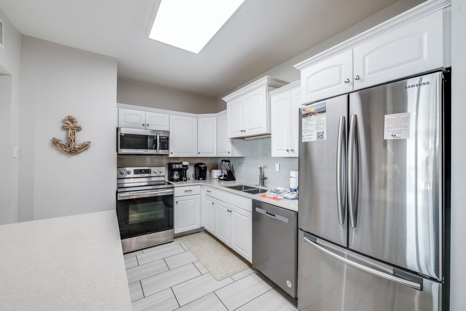 Your fully equipped kitchen features stainless steel appliances, white cabinetry, and natural light from above—perfect for preparing meals during your stay.
