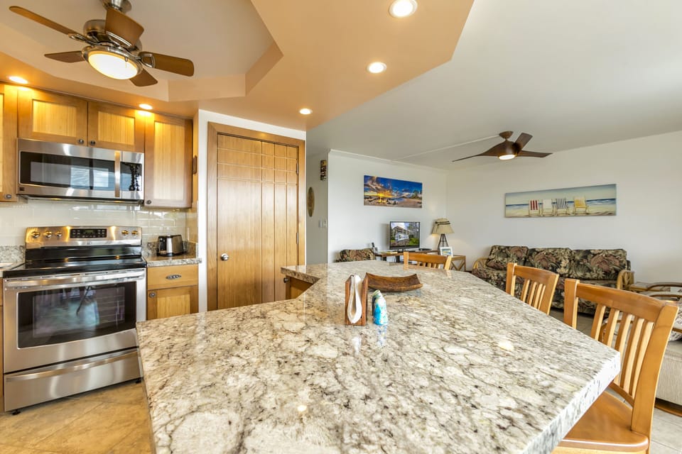 Your open-concept living space blends kitchen and lounge seamlessly, with granite counters, modern appliances, and coastal-themed décor inviting you to relax and feel at home.